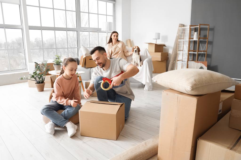 Little girl with her father taping cardboard box in room on moving day